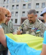 Олег Громадський (у центрі) ставить підпис на прапорі полтавських волонтерів.