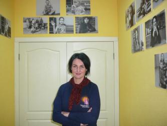 Очільниця притулку для жінок Олена Чикурова, навколо неї на стінах — світлини колишніх клієнтів.