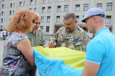 Олег Громадський (у центрі) ставить підпис на прапорі полтавських волонтерів.